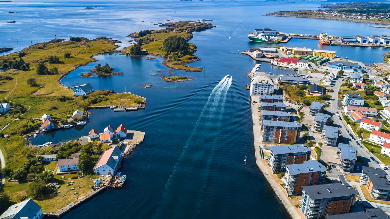 Luftaufnahme eines Küstenbereichs in Haugesund, Norwegen, mit einem Boot, das durch ruhige Gewässer fährt | MSC Cruises