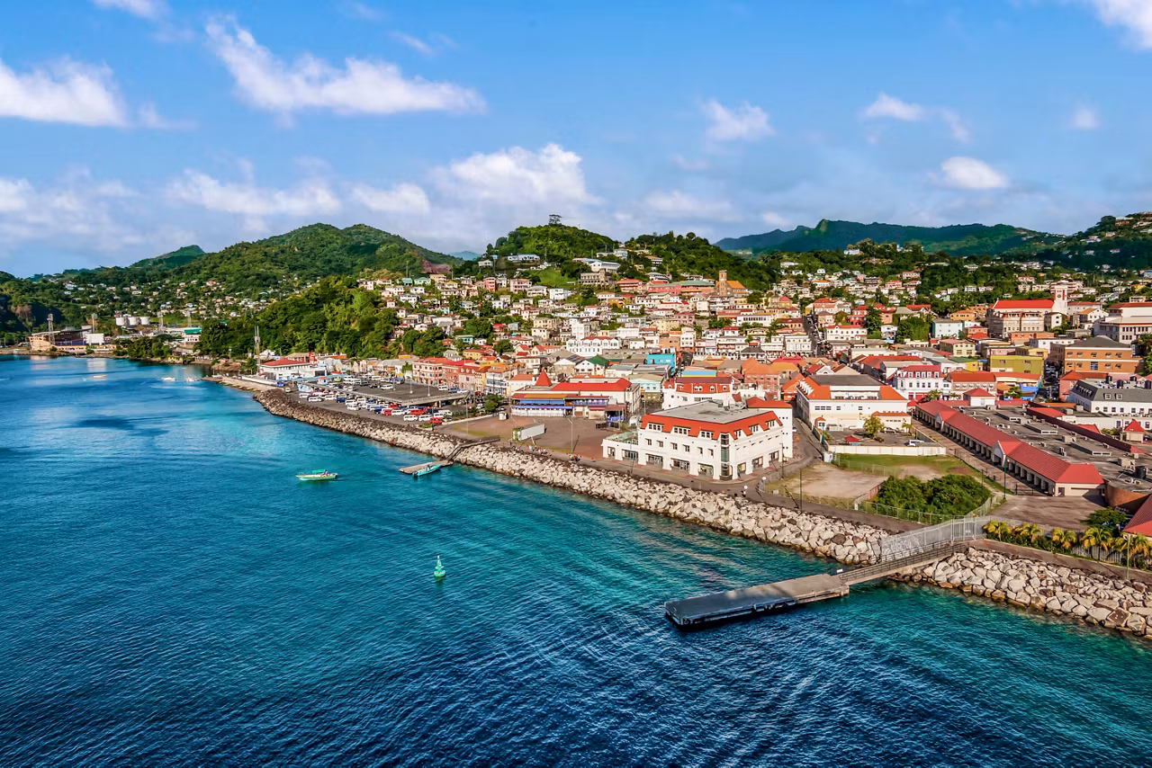Une vue côtière vibrante de Saint-Georges avec des bâtiments colorés au bord de la mer turquoise et du ciel bleu clair | MSC Croisières