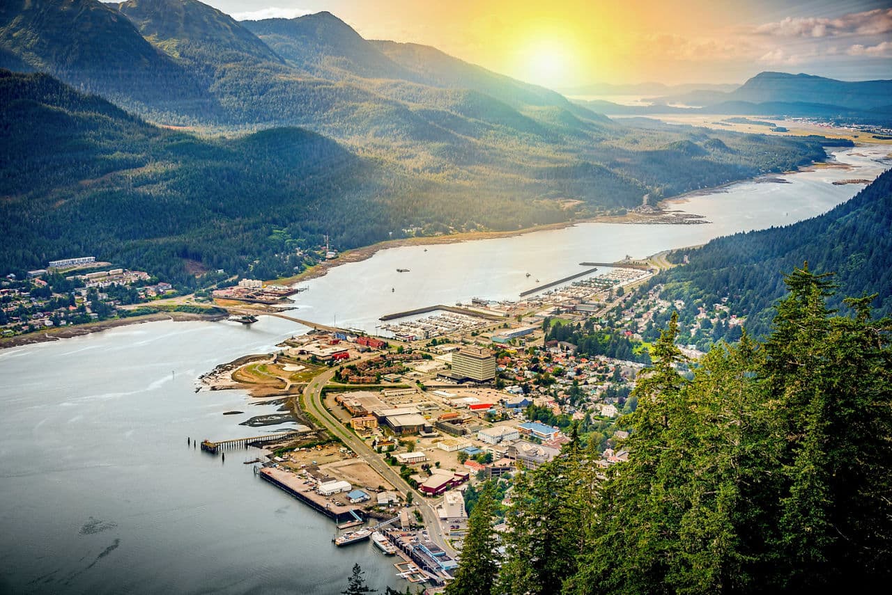 Eine atemberaubende Luftaufnahme von Juneau, Alaska, die Berge und ein ruhiges Meer bei Sonnenaufgang zeigt | MSC Cruises