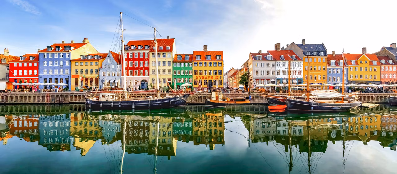 Edifici colorati fiancheggiano il Porto di Nyhavn, riflettendosi magnificamente nelle acque calme, invitando all'esplorazione e all'avventura | MSC Crociere